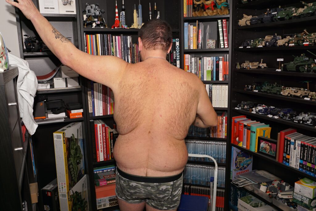 nur mit Unterhose vor einem Bücherregal