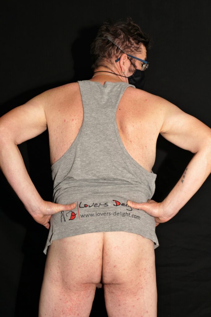 mit hoch gezogenen "Lovers Delight" T-Shirt vor einer schwarzen Leinwand